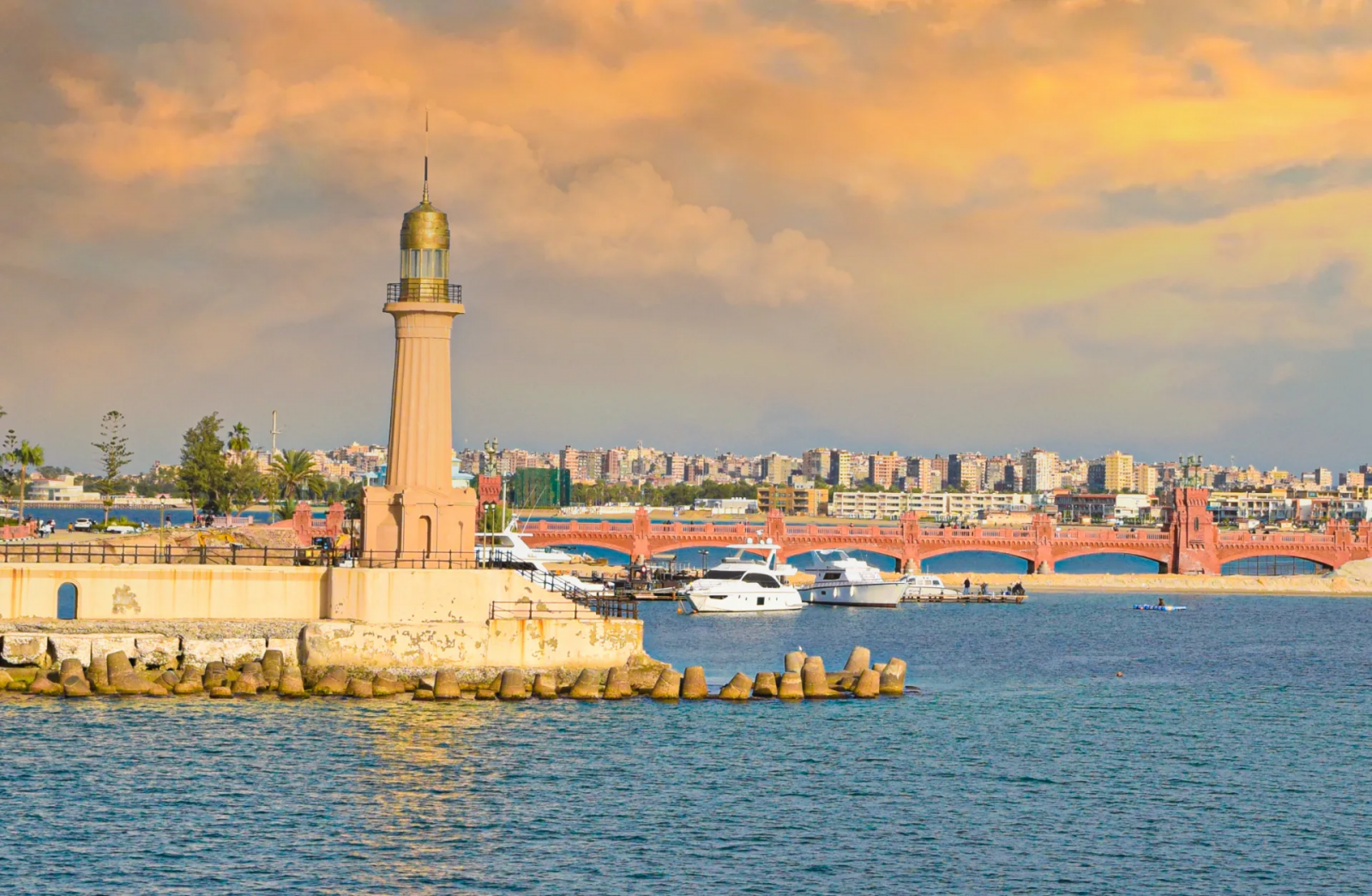 مشهد بديع لفنار تاريخي بالاسكندرية.. أنواره الخافتة تودّع شمس المغيب الغارقة في البحر